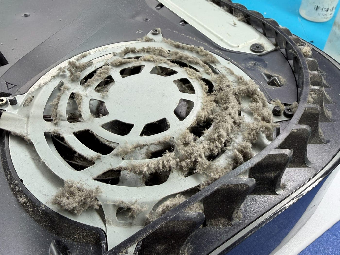 Ventilador de una PlayStation 5 cubierto de polvo y pelusa visto desde el interior